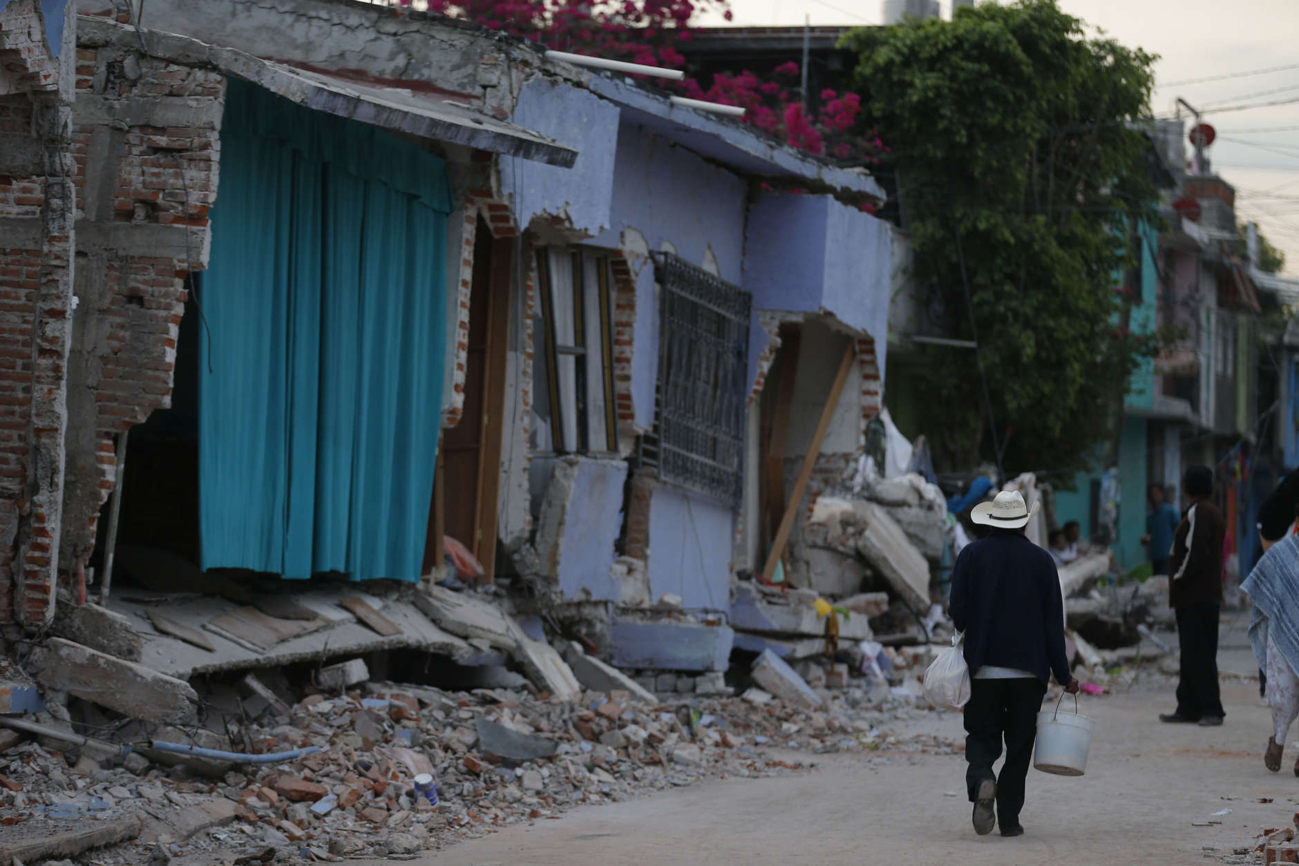 A man walks past homes damaged by a 7.1 earthquake, in Jojutla, Morelos state, Mexico, Wednesday, Sept. 20, 2017. Police, firefighters and ordinary Mexicans are digging frantically through the rubble of collapsed schools, homes and apartment buildings, looking for survivors of Mexico's deadliest earthquake in decades as the number of confirmed fatalities climbed to 248. (AP Photo/Eduardo Verdugo)