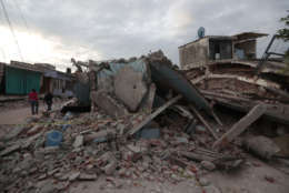 Residents walk past buildings demolished by a 7.1 earthquake, in Jojutla, Morelos state, Mexico, Wednesday, Sept. 20, 2017. Police, firefighters and ordinary Mexicans are digging frantically through the rubble of collapsed schools, homes and apartment buildings, looking for survivors of Mexico's deadliest earthquake in decades as the number of confirmed fatalities climbed to 248. (AP Photo/Eduardo Verdugo)