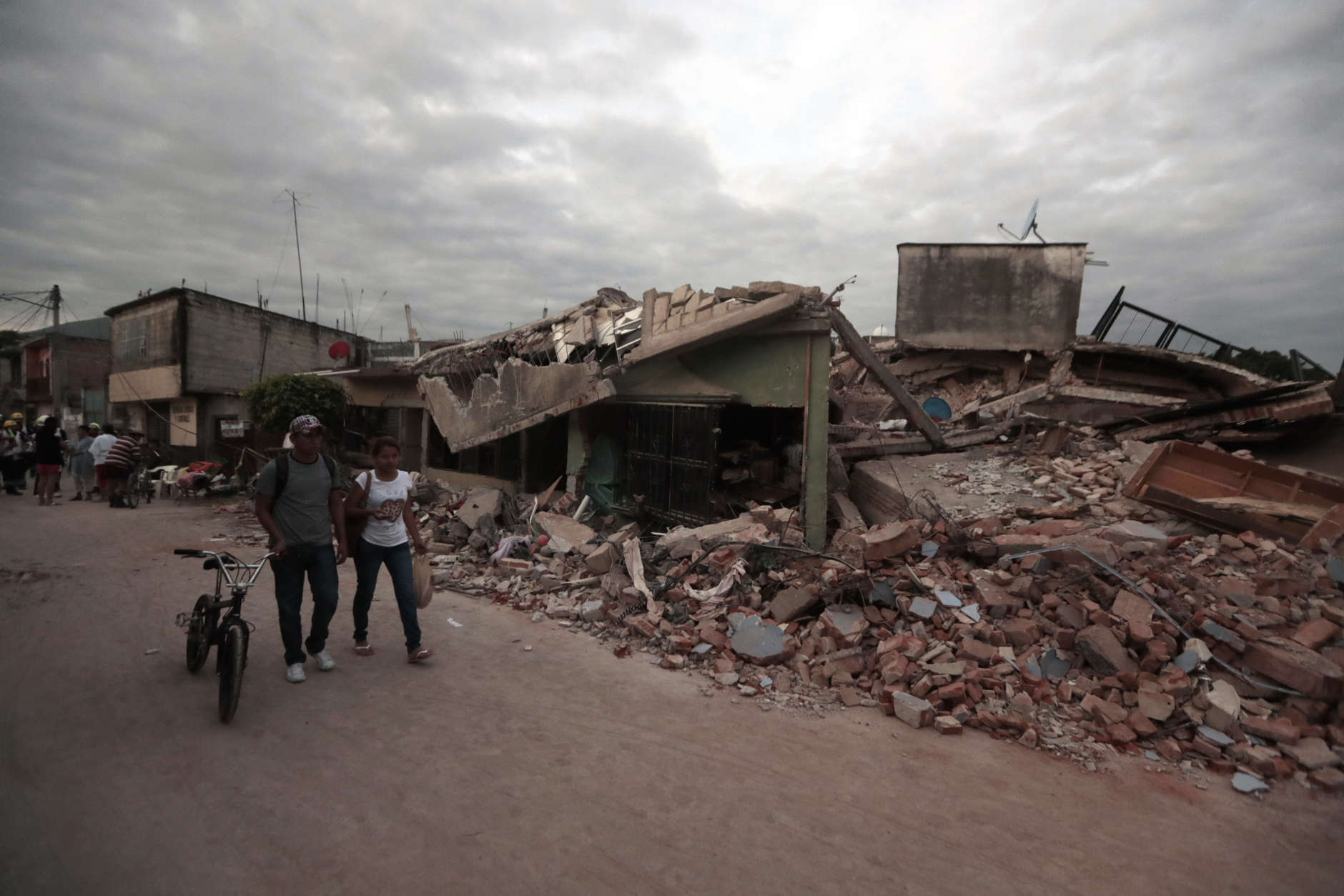 Residents walk past buildings demolished by a 7.1 earthquake, in Jojutla, Morelos state, Mexico, Wednesday, Sept. 20, 2017. Police, firefighters and ordinary Mexicans are digging frantically through the rubble of collapsed schools, homes and apartment buildings, looking for survivors of Mexico's deadliest earthquake in decades as the number of confirmed fatalities climbed to 248. (AP Photo/Eduardo Verdugo)