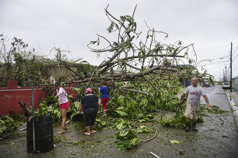 A family helps clean the road after Hurricane Maria hit the eastern region of the island, in Humacao, Puerto Rico, Tuesday, September 20, 2017. The strongest hurricane to hit Puerto Rico in more than 80 years destroyed hundreds of homes, knocked out power across the entire island and turned some streets into raging rivers in an onslaught that could plunge the U.S. territory deeper into financial crisis. (AP Photo/Carlos Giusti)