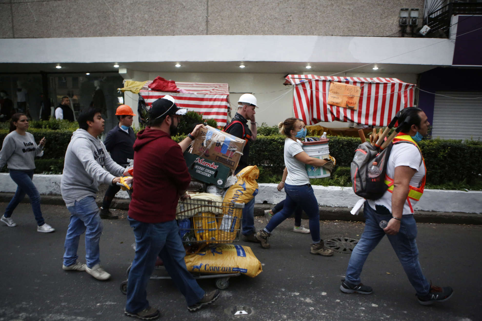 Volunteers offering their services at sites of earthquake damage mingle with people taking donations of pet food to a collection center, as they walk along Insurgentes Avenue in the Roma neighborhood in Mexico City, Wednesday, Sept. 20, 2017. City residents are roaming the streets looking for ways to help in the rescue and recovery effort, and thousands have participated in removing debris, organizing donations, directing traffic, and distributing food and water. (AP Photo/Rebecca Blackwell)