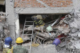 A rescue worker climbs up into an apartment building whose first four floors collapsed in the Lindavista neighborhood of Mexico City, Wednesday, Sept. 20, 2017. People by the millions rushed from homes and offices across central Mexico, after a 7.1 earthquake, sometimes watching as buildings they had just fled fell behind them with an eruption of dust and debris. (AP Photo/Rebecca Blackwell)