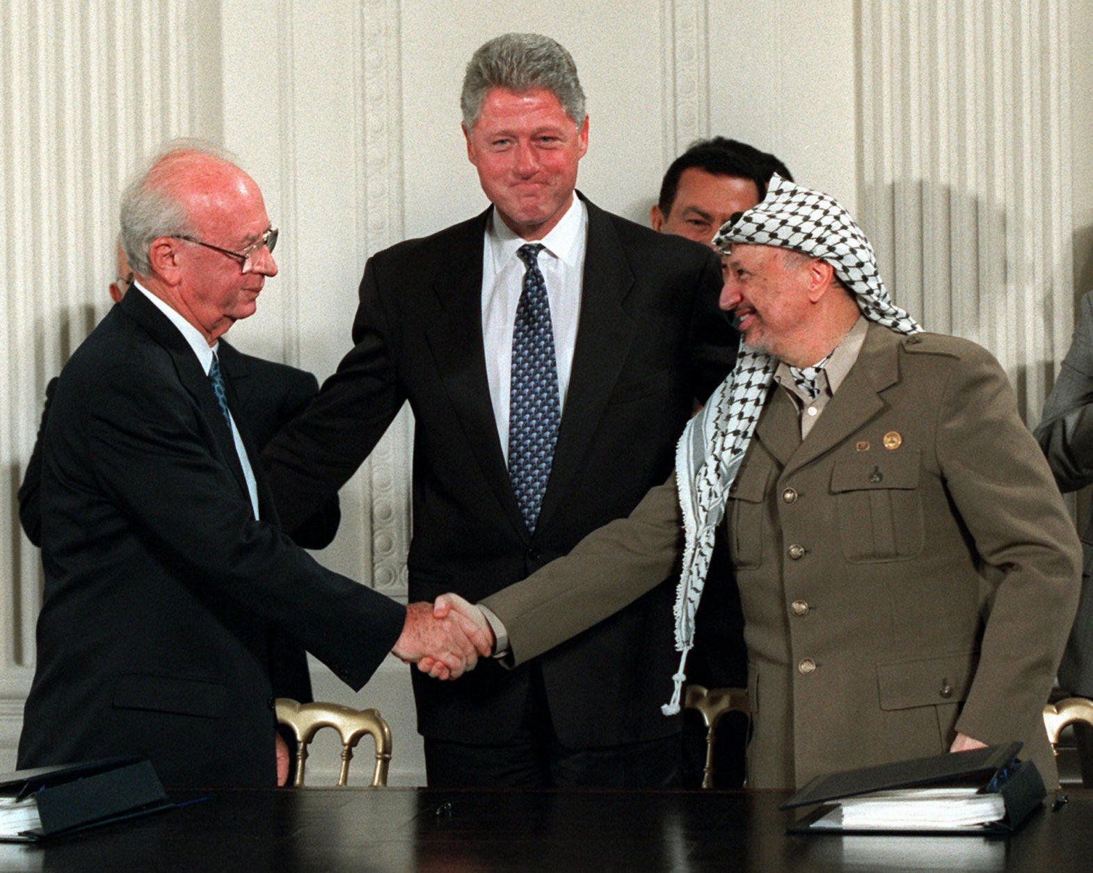 FILE - Sept. 28, 1995 file photo shows President Bill Clinton gesturing toward Israeli Prime Minister Yitzhak Rabin, left, and PLO leader Yasser Arafat shaking hands in the East Room of the White House  after the Mideast accord signing. The contours of an Israeli-Palestinian peace deal are clear, we are told. If only the two sides would finally summon up the vision, the will and the courage, then the outcome is largely preordained, it is said: Two states roughly along the pre-1967 borders with Jerusalem as a shared capital and some elegant solution for the Palestinian refugees.(AP Photo/Doug Mills, File)