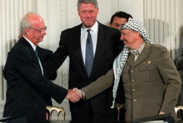 FILE - Sept. 28, 1995 file photo shows President Bill Clinton gesturing toward Israeli Prime Minister Yitzhak Rabin, left, and PLO leader Yasser Arafat shaking hands in the East Room of the White House  after the Mideast accord signing. The contours of an Israeli-Palestinian peace deal are clear, we are told. If only the two sides would finally summon up the vision, the will and the courage, then the outcome is largely preordained, it is said: Two states roughly along the pre-1967 borders with Jerusalem as a shared capital and some elegant solution for the Palestinian refugees.(AP Photo/Doug Mills, File)