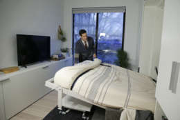 In this Dec. 22, 2015 photo, Stage 3 Properties co-founder Christopher Bledsoe demonstrates a retractable bed that turns into a sofa when stored inside one of the apartment units at the Carmel Place building in New York. As the city-sponsored micro-apartment project nears completion, its setting an example for tiny dwellings that the nations biggest city sees as an aid to easing its affordable housing crunch. (AP Photo/Julie Jacobson)