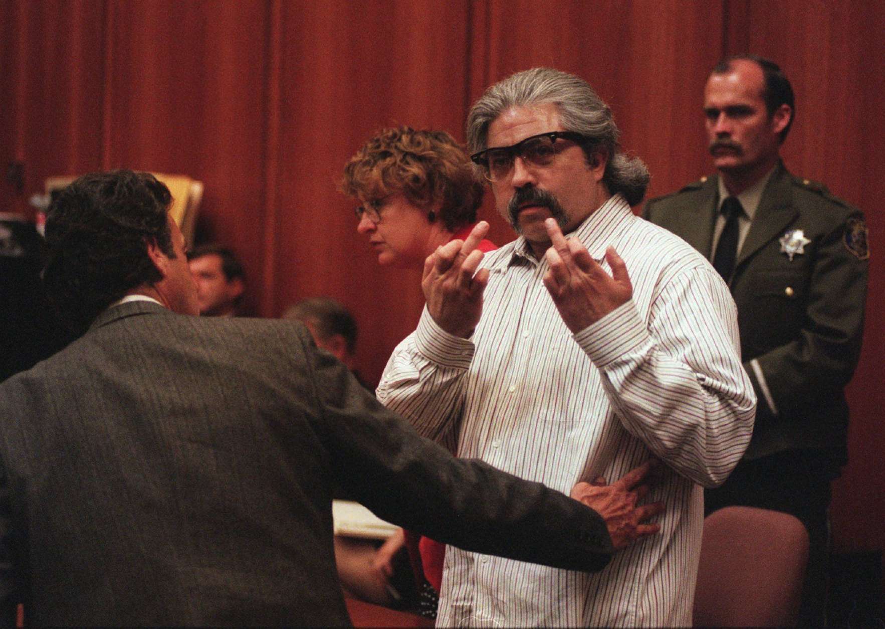 Richard Allen Davis, found guilty of the murder of Polly Klaas in San Jose on Tuesday, June 18, 1996, gestures toward the television camera after the verdict.  He is restrained by his lawyer defense counsel Barry Collins.  Behind is his other attorney Lorena Chandler. (AP Photo/John Burgess)