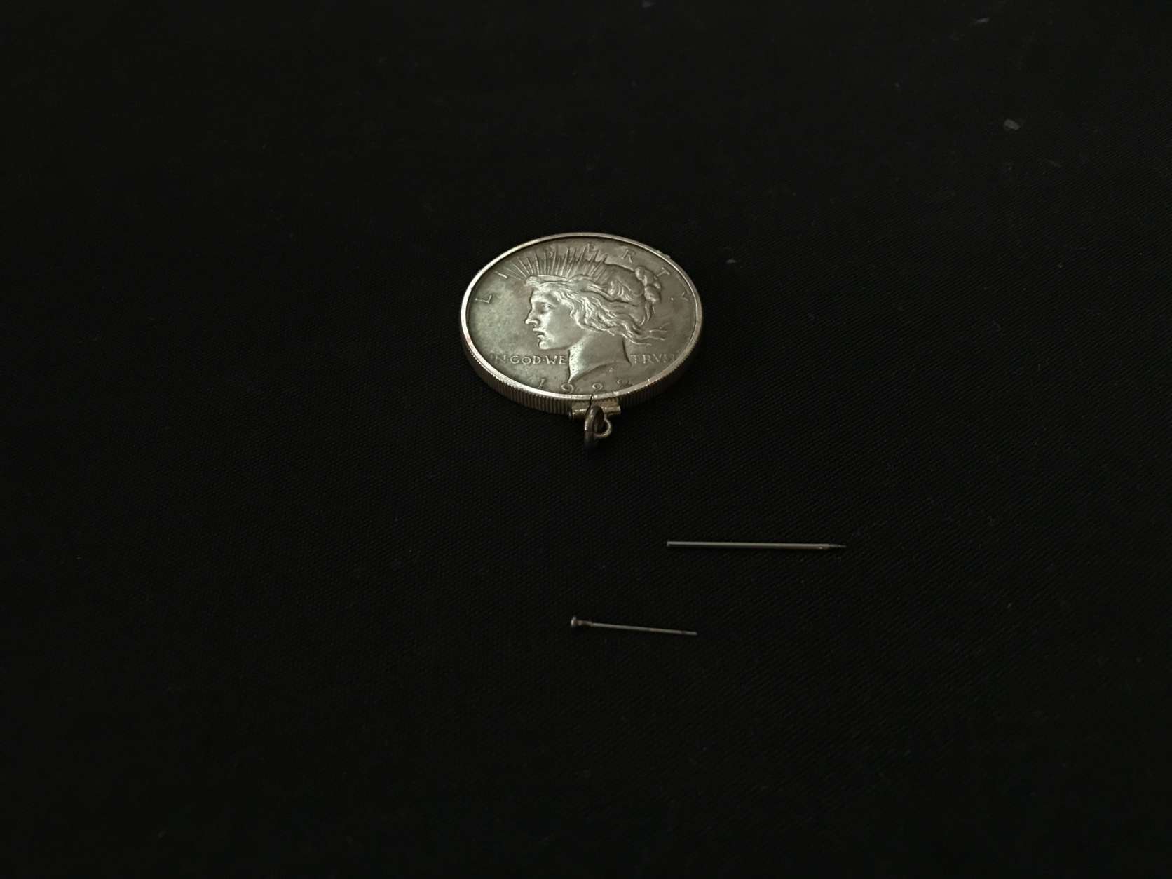 A "concealment coin," made for U2 spy plane missions, contained a spring-loaded pin (also pictured) that was loaded with a lethal toxin. (WTOP/Ginger Whitaker)