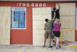CORRECTS CITY - Cyber School Supply Christopher Rodriguez is supported as he installs wood panels over a storefront window in preparation for Hurricane Irma, in Toa Baja, Puerto Rico, Tuesday, Sept. 5, 2017. Irma grew into a dangerous Category 5 storm, the most powerful seen in the Atlantic in over a decade, and roared toward islands in the northeast Caribbean Tuesday. (AP Photo/Carlos Giusti)