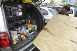After loading the back of her vehicle with food Maria Minier loads a recently purchased wood panel to be used in preparation for Hurricane Irma, in Carolina, Puerto Rico, Tuesday, Sept. 5, 2017. Irma grew into a dangerous Category 5 storm, the most powerful seen in the Atlantic in over a decade, and roared toward islands in the northeast Caribbean Tuesday. (AP Photo/Carlos Giusti)