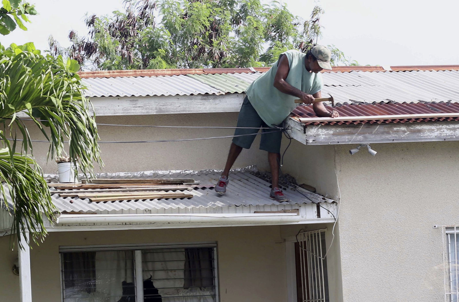 A homeowner makes last minute repairs to his roof in preparation for Hurricane Irma, in St. John's, Antigua and Barbuda, Tuesday, Sept. 5, 2017.  Irma grew into a dangerous Category 5 storm, the most powerful seen in the Atlantic in over a decade, and roared toward islands in the northeast Caribbean Tuesday on a path that could eventually take it to the United States. (AP Photo/Johnny Jno-Baptiste)