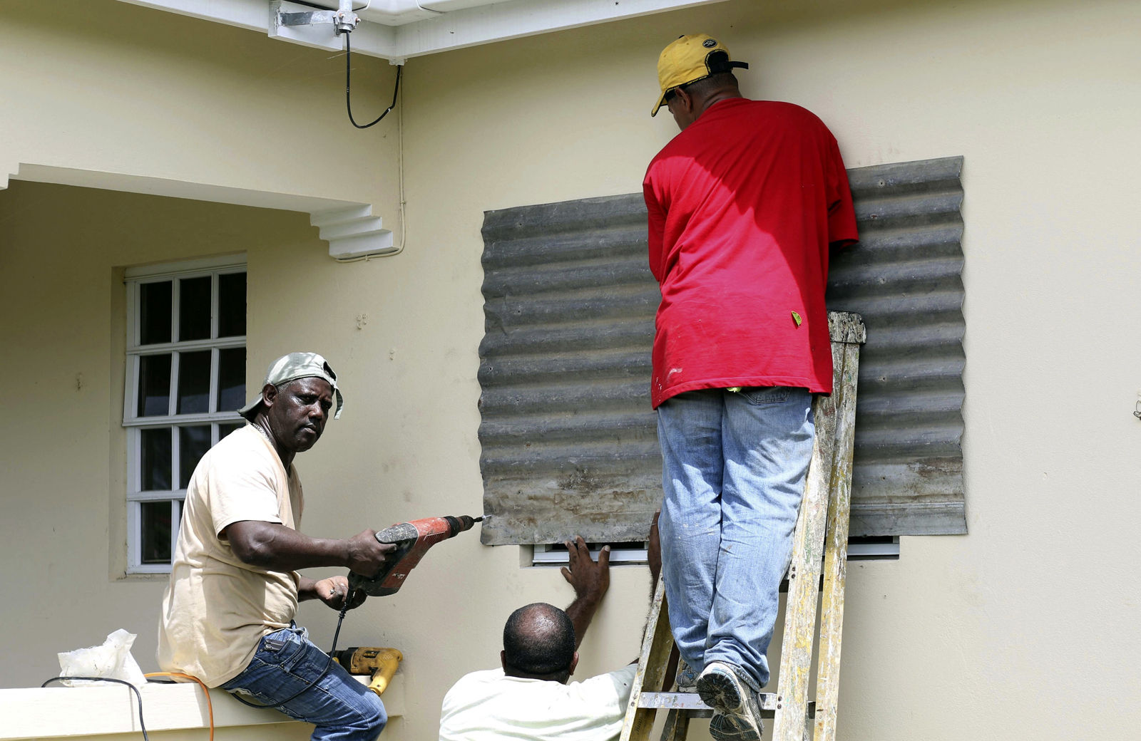 People put up a steel sheet over a window in preparation for Hurricane Irma, in Fort Road, St. John's, Antigua and Barbuda, Tuesday, Sept. 5, 2017.  Irma grew into a dangerous Category 5 storm, the most powerful seen in the Atlantic in over a decade, and roared toward islands in the northeast Caribbean Tuesday on a path that could eventually take it to the United States. (AP Photo/Johnny Jno-Baptiste)