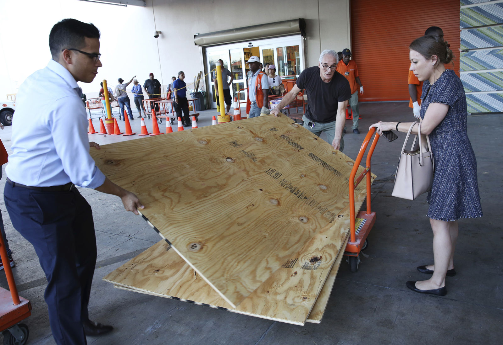 Carla Perroni Aguilera of Miami Beach, Fla., holds a cart as her husband Ronald Aguilera and her father Joe Perroni load sheets of plywood at The Home Depot store in North Miami, Fla., Wednesday, Sept. 6, 2017. Florida residents are preparing for the possible landfall of Hurricane Irma, the most powerful Atlantic Ocean hurricane in recorded history. (AP Photo/Marta Lavandier)