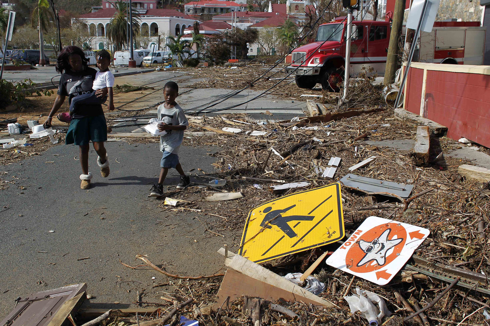 A woman with her two children walk past debris left by Hurricane Irma in Charlotte Amalie, St. Thomas, U.S. Virgin Islands, Sunday, Sept. 10, 2017.  The storm ravaged such lush resort islands as St. Martin, St. Barts, St. Thomas, Barbuda and Anguilla. (AP Photo/Ricardo Arduengo)