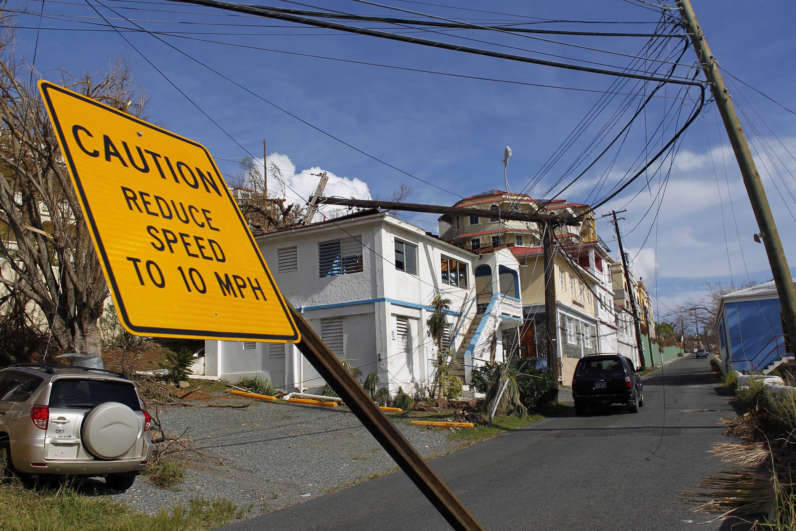 A speed limit sign stands tilted and a  power line that snapped it half lays on a building, after the passage of Hurricane Irma in Charlotte Amalie, St. Thomas, U.S. Virgin Islands, Sunday, Sept. 10, 2017.  The storm ravaged such lush resort islands as St. Martin, St. Barts, St. Thomas, Barbuda and Anguilla. (AP Photo/Ricardo Arduengo)