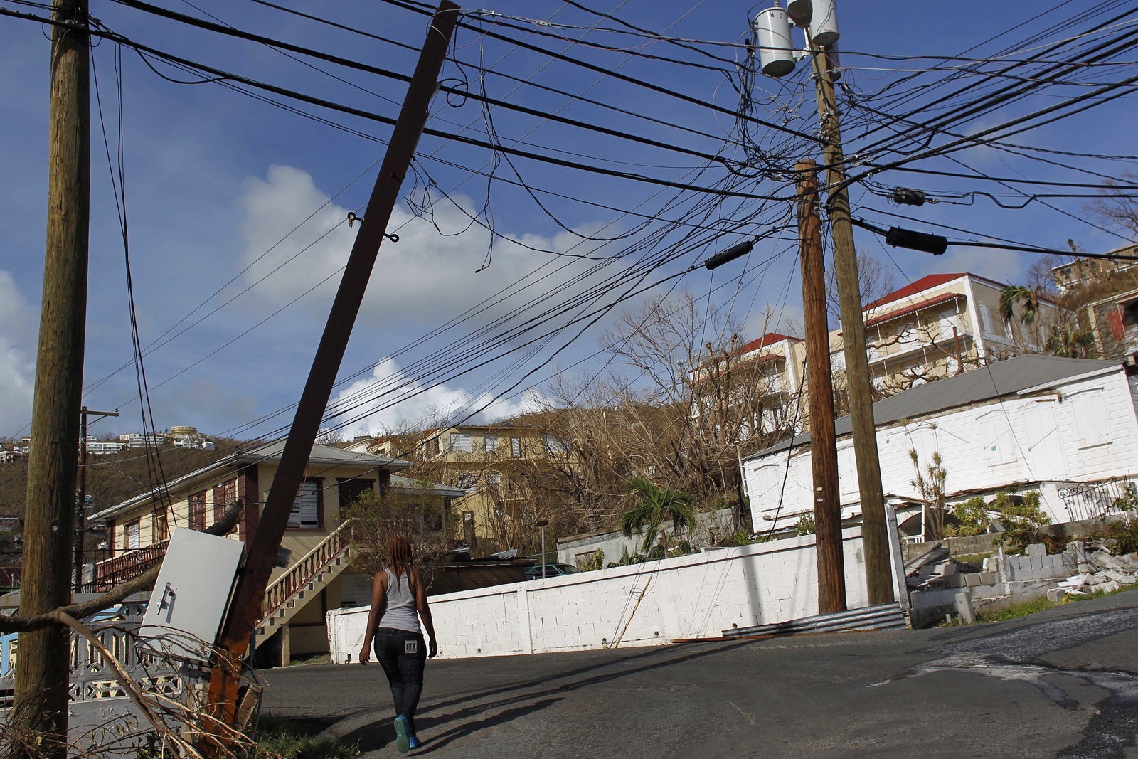 A woman walks under affected power lines after the passage of Hurricane Irma in Charlotte Amalie, St. Thomas, U.S. Virgin Islands, Sunday, Sept. 10, 2017.  The storm ravaged such lush resort islands as St. Martin, St. Barts, St. Thomas, Barbuda and Anguilla. (AP Photo/Ricardo Arduengo)