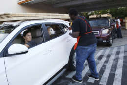 Beatriz Bustamante and her dog Simon wait as Qawrence Symonette secures sheets of plywood on her car at The Home Depot store in North Miami, Fla., Wednesday, Sept. 6, 2017. Florida residents are preparing for the possible landfall of Hurricane Irma, the most powerful Atlantic Ocean hurricane in recorded history. (AP Photo/Marta Lavandier)