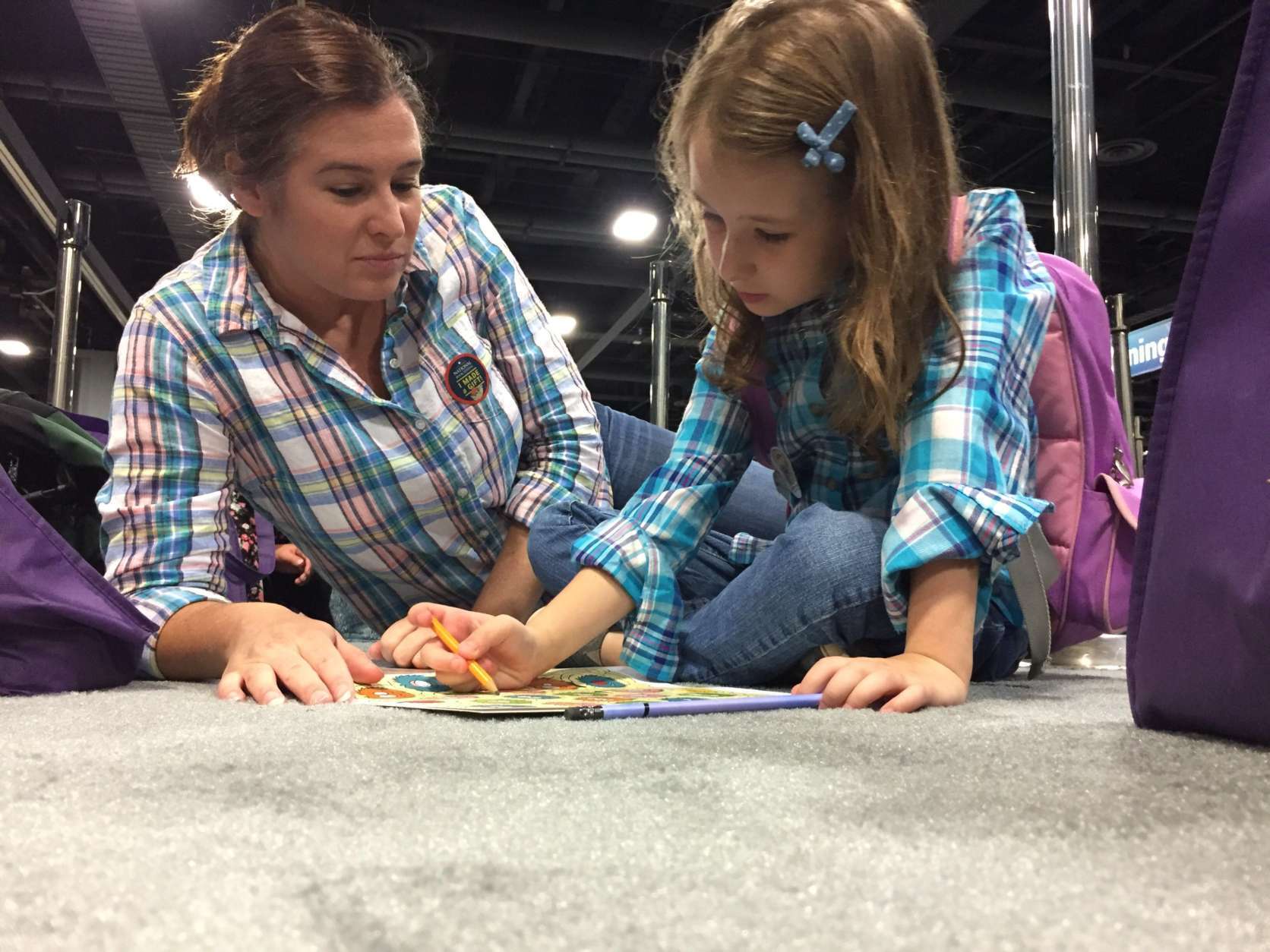 Traci Stilwell and 6-year-old daughter Amelia Begole pass the time in line at the National Book Festival by reading a book. (WTOP/Kate Ryan) 