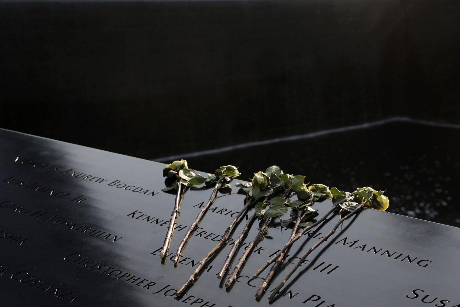 Flowers lay over the names of the victims of the 9/11 terrorist attacks before a ceremony at ground zero in New York, Monday, Sept. 11, 2017. Holding photos and reading names of loved ones lost 16 years ago, 9/11 victims' relatives marked the anniversary of the attacks at ground zero on Monday with a solemn and personal ceremony. (AP Photo/Seth Wenig)