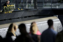 A man places flowers at the edge of the north waterfall pool during a ceremony at ground zero in New York, Monday, Sept. 11, 2017. Holding photos and reading names of loved ones lost 16 years ago, 9/11 victims' relatives marked the anniversary of the attacks at ground with a solemn and personal ceremony. (AP Photo/Seth Wenig)