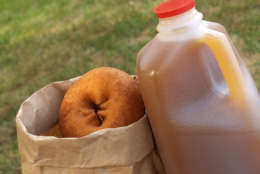 a half-gallon of apple cider beside a bag of donuts