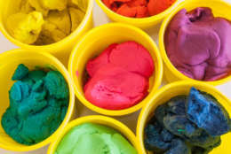 Colorful play dough in yellow cans in white background.