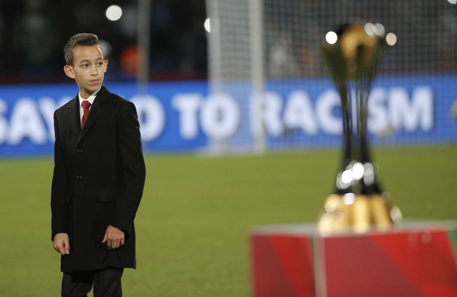The son of Morocco's King Mohammed VI, Moulay Hassan, stands next to the trophy ahead of the final soccer match between Real Madrid and San Lorenzo at the Club World Cup soccer tournament in Marrakech, Morocco, Saturday, Dec. 20, 2014. (AP Photo/Christophe Ena)