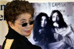 ** FILE ** In this Dec. 9, 2002 file photo, Yoko Ono smiles in front of a famous photo of her and her husband, the late John Lennon, during a news conference in Saitama, Japan. Ono is suing the producers of a movie that challenges the concept of Darwinian evolution, saying they used the song "Imagine" without her permission and led the blogosphere to accuse her of "selling out." (AP Photo/Itsuo Inouye, FILE)