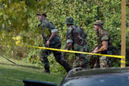 A heavly-armed tactical team walks into the woods around the area near Tasker Middle School in Bowie, Md. Monday, Oct. 7, 2002 near where a 13-year-old boy was shot and critically wounded as his aunt dropped him off at school, bringing fresh terror to the Washington area where a sniper killed six people last week. (AP Photo/J.Scott Applewhite)