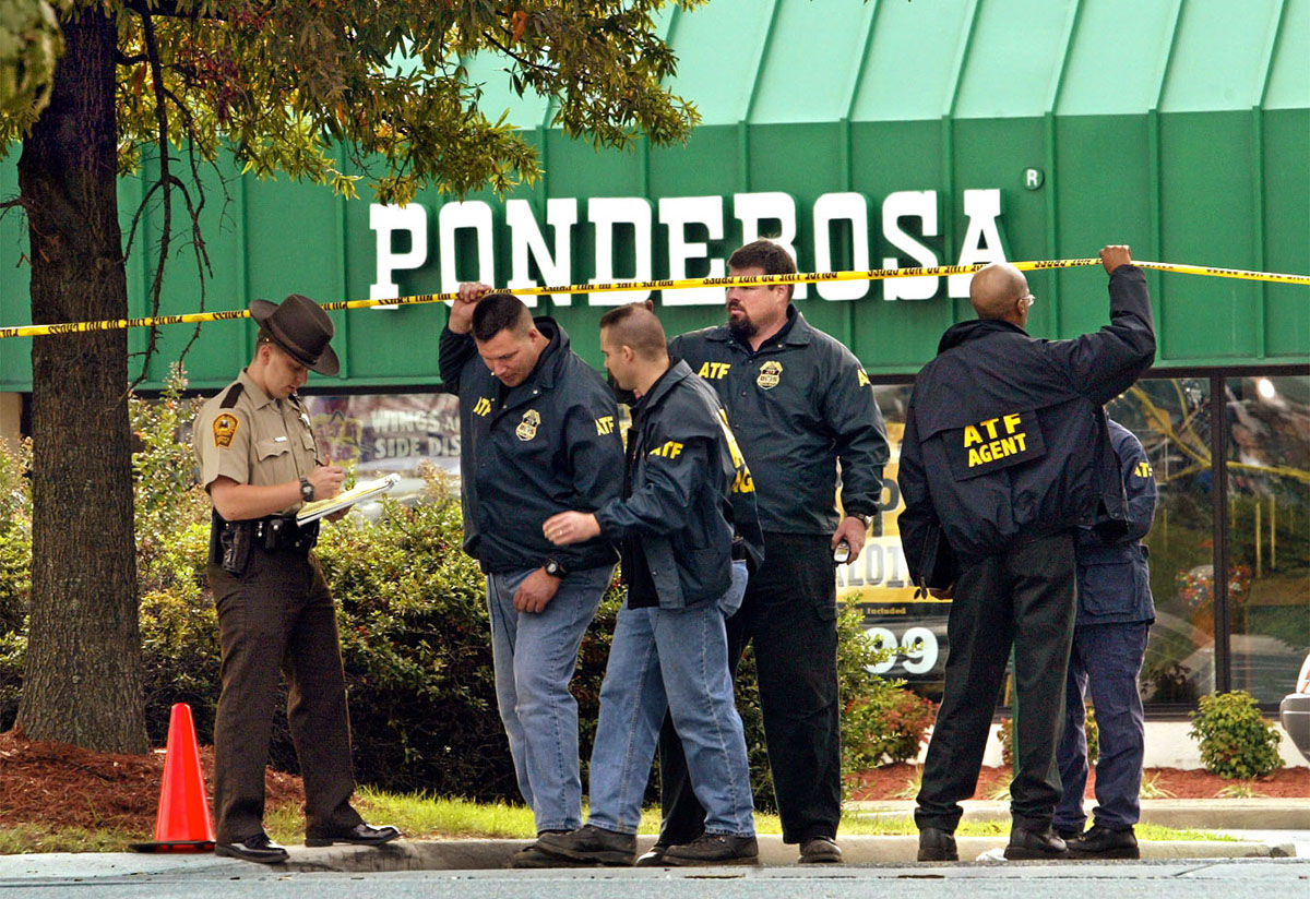 Investigators from the Bureau of Alcohol, Tobacco and Firearms pass under yellow crime-scene tape outside a Ponderosa Steakhouse in Ashland, Va., Sunday, Oct. 20, 2002, where a man was shot Saturday night. Authorities finished a painstaking search around the steakhouse where the 37-year-old man was critically wounded and said Sunday they are assuming the attack is the work of the Washington-area sniper. (AP Photo/J. Scott Applewhite)