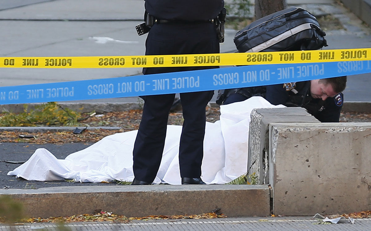 A paramedic looks at a body covered under a white sheet along the bike path Tuesday Oct. 31, 2017, in New York. A motorist drove onto a busy bicycle path near the World Trade Center memorial and struck several people Tuesday, police and witnesses said. (AP Photo/Bebeto Matthews)
