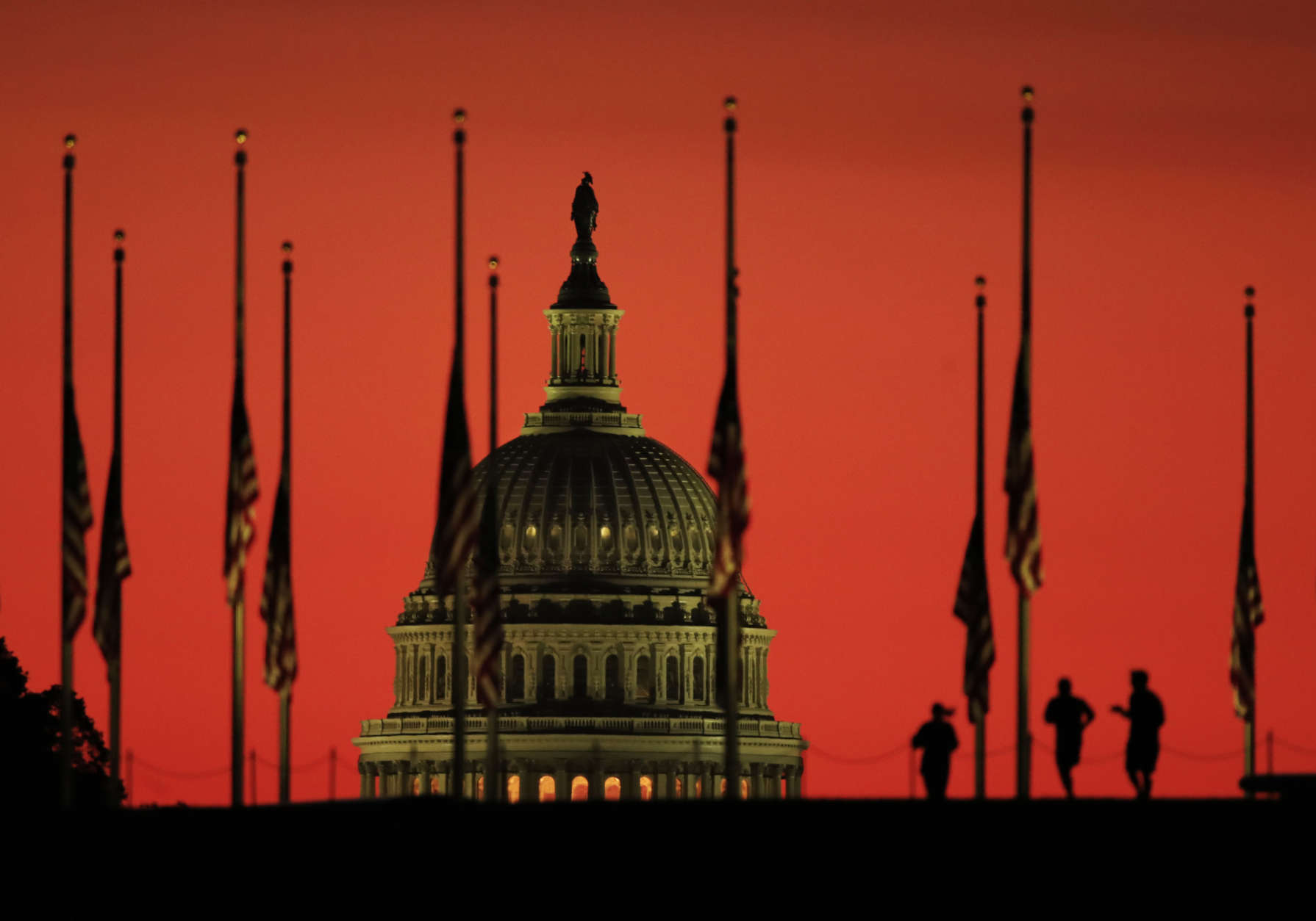 The U.S. Capitol dome backdrops flags at half-staff in honor of the victims killed in the Las Vegas shooting as the sun rises on Tuesday, Oct. 3, 2017, at the foot of the Washington Monument on the National Mall in Washington. (AP Photo/Manuel Balce Ceneta)