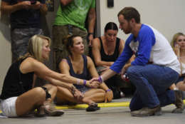 People hold hands in prayer while hiding inside the Sands Corporation plane hangar after a mass shooting in which dozens were killed at the Route 91 Harvest Festival on Sunday, Oct. 1, 2017, in Las Vegas. (Al Powers/Invision/AP)