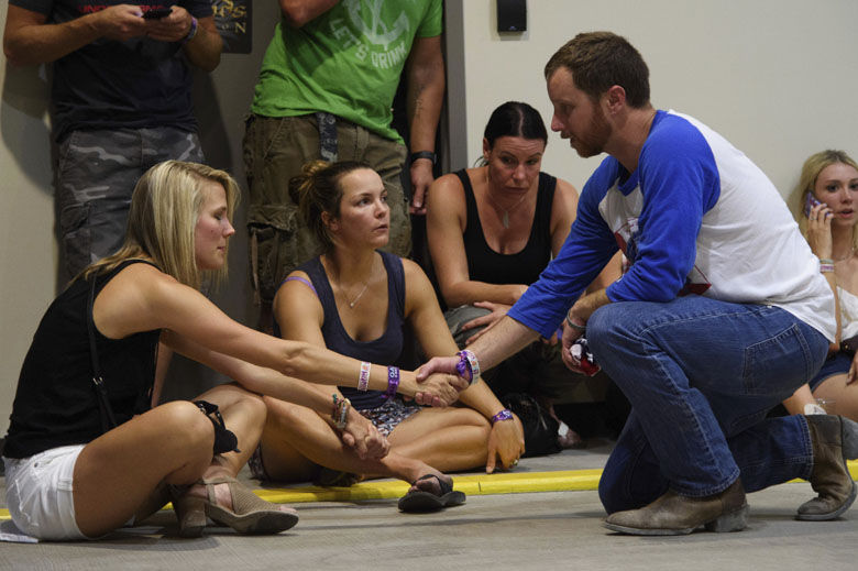 People hold hands in prayer while hiding inside the Sands Corporation plane hangar after a mass shooting in which dozens were killed at the Route 91 Harvest Festival on Sunday, Oct. 1, 2017, in Las Vegas. (Al Powers/Invision/AP)