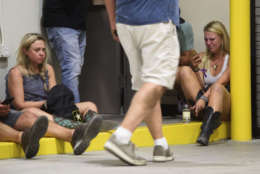 A young woman checks her phone while hiding inside the Sands Corporation plane hangar after a mass shooting in which dozens were killed at the Route 91 Harvest country festival on Sunday, Oct. 1, 2017, in Las Vegas. (Al Powers/Invision/AP)