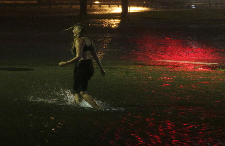 A woman wades through a flooded Water St. in downtown Mobile, Ala., during Hurricane Nate, Sunday, Oct. 8, 2017, in Mobile, Ala.  Hurricane Nate came ashore along Mississippi's coast outside Biloxi early Sunday, the first hurricane to make landfall in the state since Hurricane Katrina in 2005.(AP Photo/Brynn Anderson)
