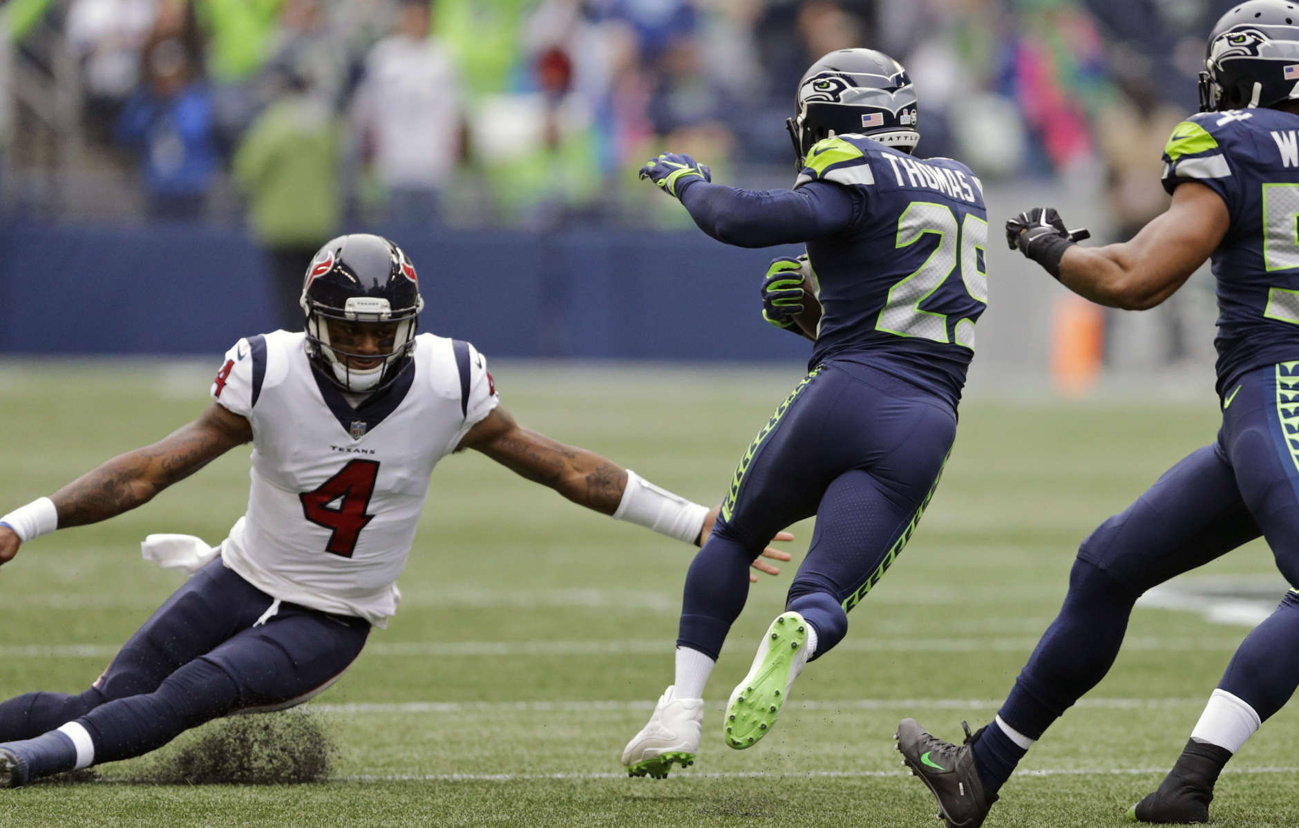 Seattle Seahawks free safety Earl Thomas, second from left, avoids a tackle-attempt by Houston Texans quarterback Deshaun Watson (4) after intercepting a pass from Watson in the first half of an NFL football game, Sunday, Oct. 29, 2017, in Seattle. Thomas returned the interception 78 yards for a touchdown. (AP Photo/Stephen Brashear)