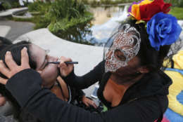 Cristina Ramirez, right, helps Alcira Tabon paint her face as they prepare to stroll along the Lincoln Road pedestrian mall for Halloween, Tuesday, Oct. 31, 2017, in the South Beach neighborhood of Miami Beach, Fla. (AP Photo/Wilfredo Lee)