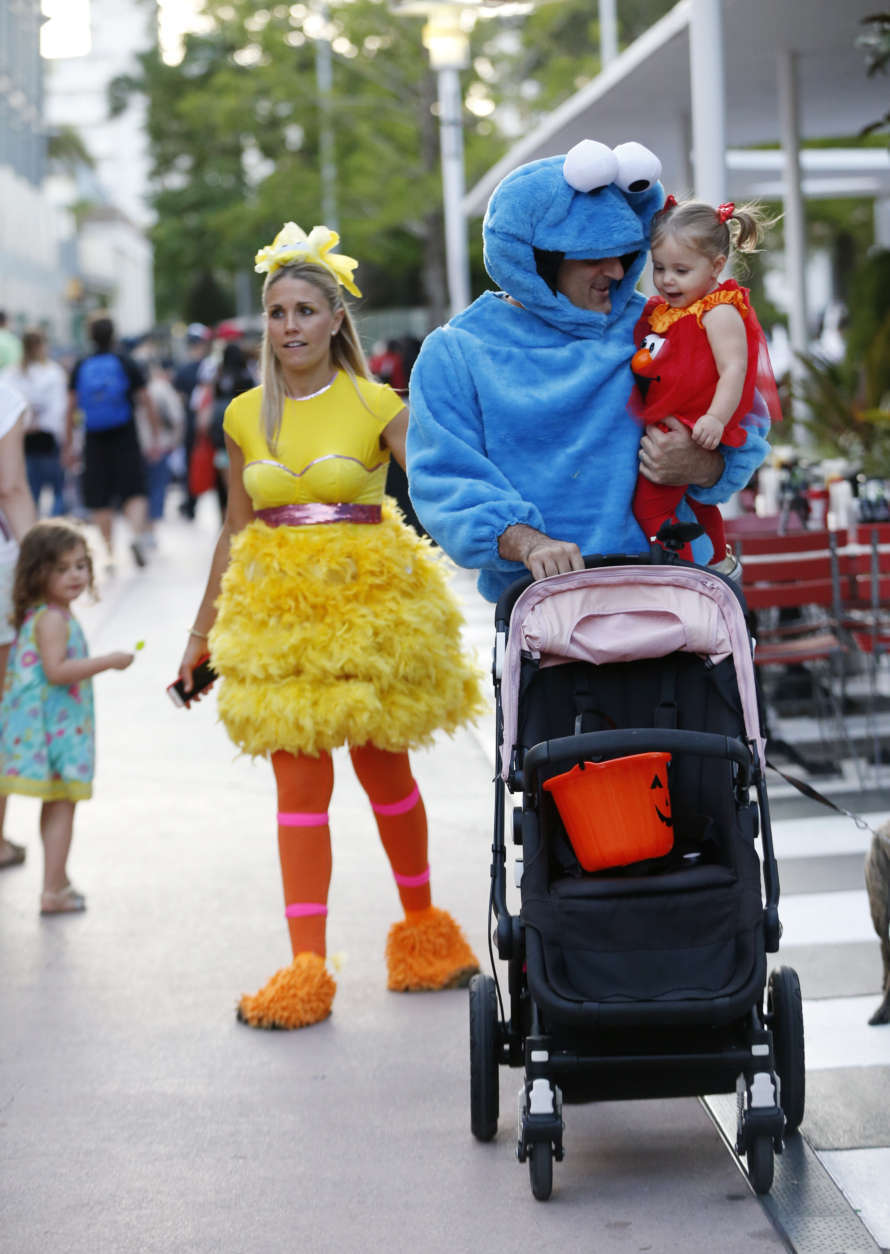 Josh Keller, center, walks with his daughter Isabel, 1, and his wife Laura as they trick-or-treat dressed up as Big Bird, Cookie Monster and Elmo along the Lincoln Road pedestrian mall for Halloween, Tuesday, Oct. 31, 2017, in the South Beach neighborhood of Miami Beach, Fla. (AP Photo/Wilfredo Lee)