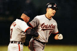 Cal Ripken Jr., of the Baltimore Orioles, shakes hands with his father, Orioles third base coach Cal Ripken Sr., as he rounds the bases after hitting a two-run homer in the seventh inning of the game with the Oakland Athletics at Oakland Coliseum, Calif., on July 13, 1991. (AP Photo/Brad Mangin)