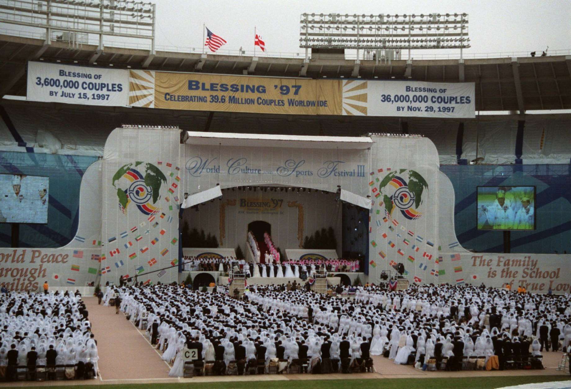 Some of the 28,000 couples participating in a marriage affirmation ceremony officiated by the Rev. and Mrs. Sun Myung Moon, founders of the Unification Church, stand as the Rev. and Mrs. Moon arrive on stage at Robert F. Kennedy Stadium Saturday, Nov. 29, 1997, in Washington. (AP Photo/Karin Cooper)