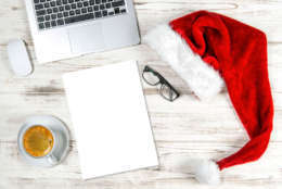 Office Desk with Computer, Coffee and Christmas Decoration. Business Holidays Concept with blank Paper Sheet
