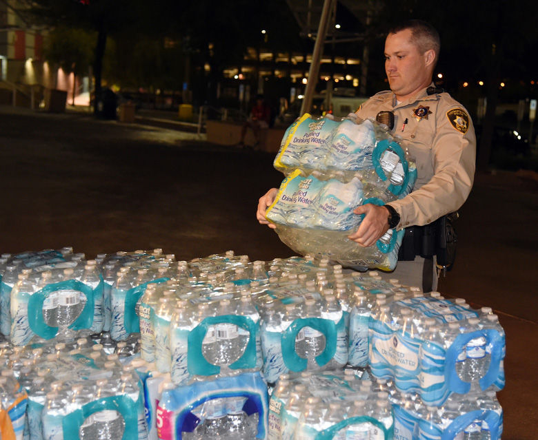 LAS VEGAS, NV - OCTOBER 02:  A Las Vegas Metropolitan Police Department officer helps deliver bottled water to people at the Thomas &amp; Mack Center after a mass shooting at a country music festival on October 2, 2017 in Las Vegas, Nevada. People who could not go to hotel-casinos that were closed after the shooting are temporarily staying at the center and residents are donating supplies. The gunman, identified as Stephen Paddock, 64, of Mesquite, Nevada, opened fire from the Mandalay Bay Resort and Casino on the music festival, leaving at least 50 people dead and hundreds injured. Police have confirmed that one suspect has been shot. The investigation is ongoing.   (Photo by Ethan Miller/Getty Images)