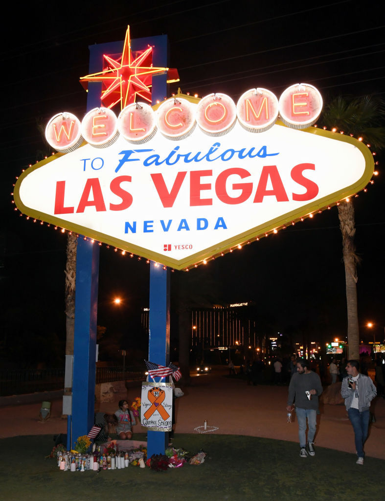 LAS VEGAS, NV - OCTOBER 03:  Visitors walk by a makeshift memorial at the base of the Welcome to Fabulous Las Vegas sign in memory of the victims of Sunday night's shooting, on October 3, 2017 in Las Vegas, Nevada. Late Sunday night, a lone gunman killed at least 59 people and injured more than 500 after he opened fire on a large crowd at the Route 91 Harvest country music festival. The massacre is one of the deadliest mass shooting events in U.S. history.  (Photo by Ethan Miller/Getty Images)