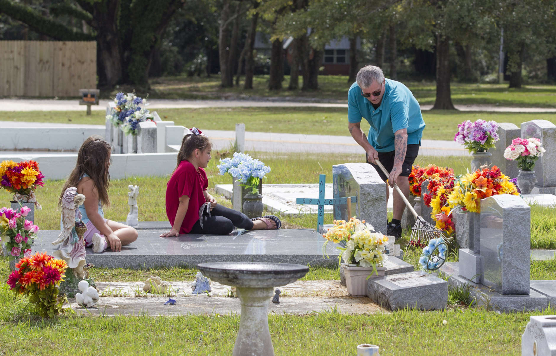 BAYOU LA BATRE, AL - OCTOBER 8:  Tracy Goleman (R) rakes up the debris and litter from Hurricane Nate from the Goleman family plot with his nieces (L-R) Natalina Nicolas, 8, and Briana Nicolas, 10 at the Oddfellows Cemetery on October 8, 2017 in Bayou La Batre, Alabama. Hurricane Nate made its second landfall along the north Mississippi Gulf Coast as a category 1 hurricane Sunday before weakening to a tropical storm.  (Photo by Mark Wallheiser/Getty Images)