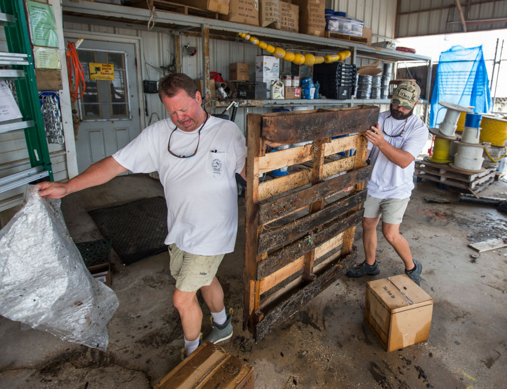 BAYOU LA BATRE, AL - OCTOBER 8:  Greg Marshall (L) and Kyle Porter clean up Marshall Marine after the store took three feet of storm surge from Hurricane Nate on October 8, 2017 in Bayou La Batre, Alabama.  Hurricane Nate made its second landfall along the north Mississippi Gulf Coast as a category 1 hurricane Sunday before weakening to a tropical storm.  (Photo by Mark Wallheiser/Getty Images)