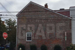 The "Chew Grape" sign in Alexandria (601 S. St. Asaph St.) emerged when plaster was removed from the side of a rowhouse. (WTOP/Jack Pointer)