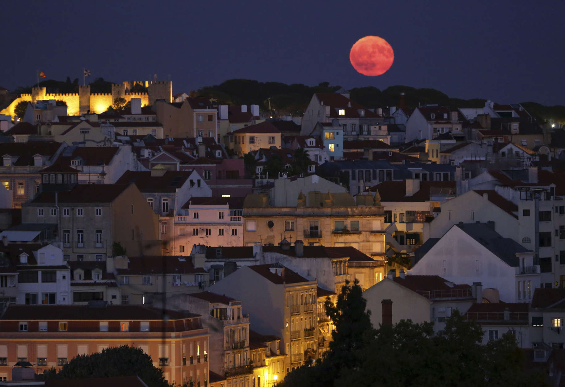 The full moon rises behind Lisbon's Saint George's castle hill as night falls Wednesday, Sept. 6 2017. (AP Photo/Armando Franca)