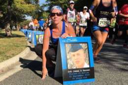 First-time Marine Corps Marathon runner poses with a photo of her cousin who died in combat seven years ago. (WTOP/Monique Blyther)
