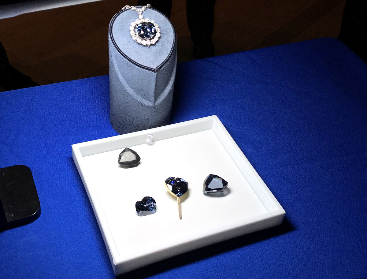 The Hope Diamond, center top, is displayed with the replicas below. At top left of the white box is a lead cast replica. The rest of the box, from left to right: Hope Diamond replica, French Blue Diamond replica and Tavernier Diamond replica. (Courtesy Smithsonian Institution)