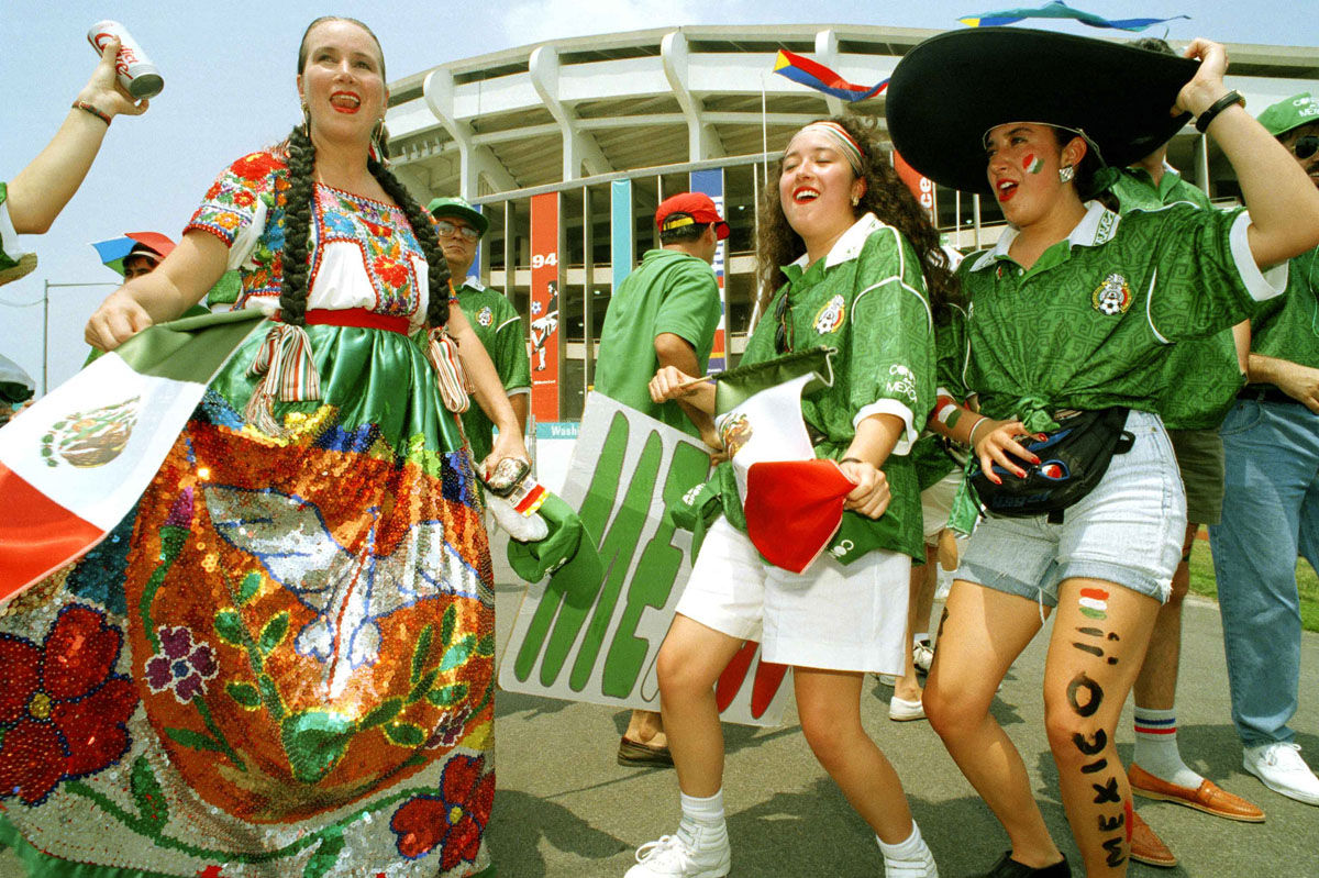 Soccer fans dressed in support of team Mexico dance, June 19, 1994, outside Washington RFK Stadium before the start of the World Cup soccer championship, Group E first round match, Mexico vs. Norway. (AP Photo/Damian Dovarganes)
